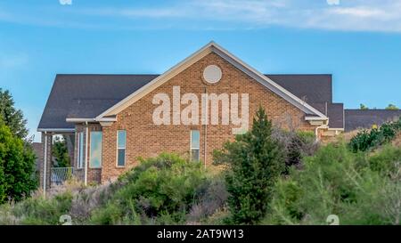 Panorama Blue sky and clouds over a home with gray roof and brick exterior wall Stock Photo