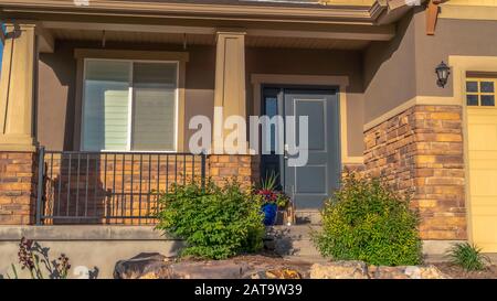 Panorama frame Home entrance with front porch gray door sidelight and garage with gable roof Stock Photo