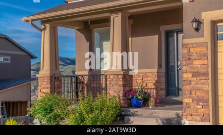 Panorama frame Home with landscaped yard and front porch against hill and sky background Stock Photo