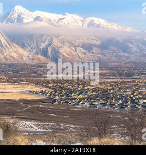 Square frame Snow covered Mount Timpanogos towering over neighborhood houses in the valley Stock Photo