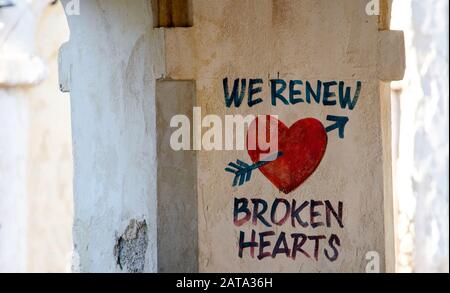 sign on a wall of a stucco building we renew broken hearts Stock Photo