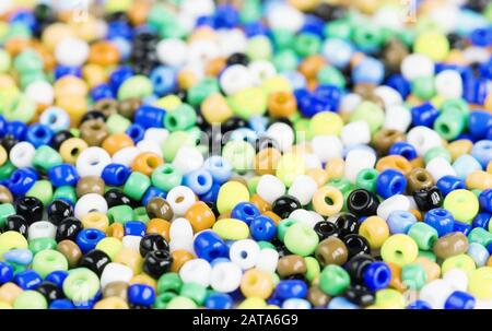 Heap of multi-colored beads for needlework are scattered on a white background Stock Photo
