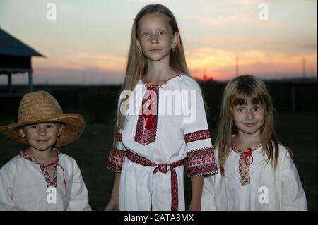 Slavic children in an embroidered shirt on a sunset background. Children are Ukrainian and Belarusians. People in national clothes. Stock Photo