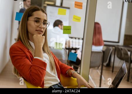 Girl listening to music on laptop as she takes a break from hard work in coworking space. Stock Photo