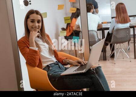 Girl listening to music on laptop as she takes a break from hard work in coworking space. Stock Photo