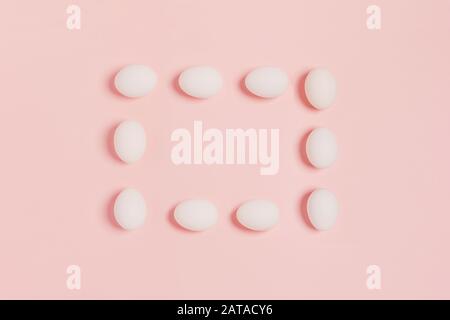 Happy Easter. Rectangular frame made of white eggs on pink background. Flat lay, top view, copy space. Stock Photo