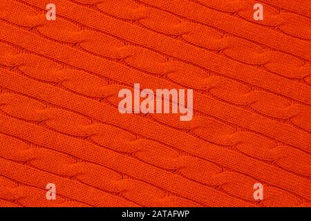 Abstract bright orange knitted background. Yarn pattern, jersey surface, knitwear wallpaper. Ornament of acrylic braids. Woolen weave Stock Photo