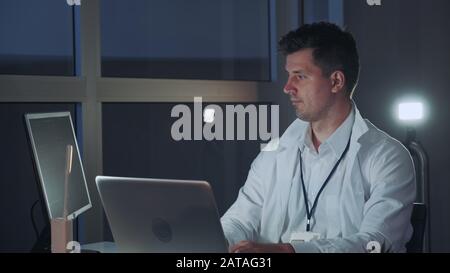 Male specialist in electronics working on the computer in modern lab. He finding new technological methods. Professional Writing on Programming Code Stock Photo