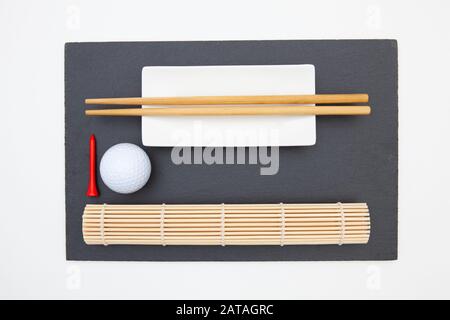 Rectangular slate plate with chopsticks for sushi and golf ball. Golf Design Stock Photo