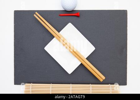 Rectangular slate plate with chopsticks for sushi and golf tee.  Golf Design Stock Photo