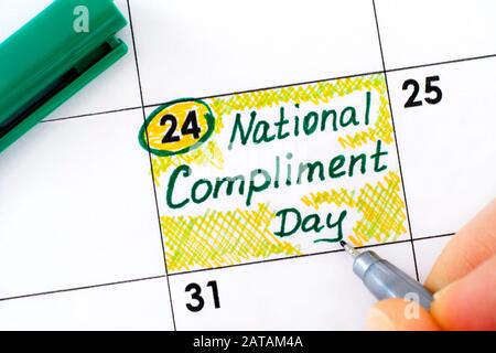 Woman fingers with pen writing reminder National Compliment Day in calendar. January 24. Stock Photo