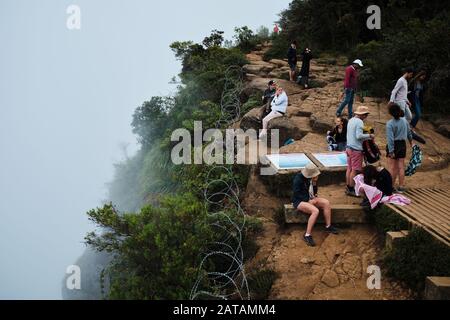 Tourists sitting at the foggy World's End in Horton Plains national park, Sri Lanka. Stock Photo