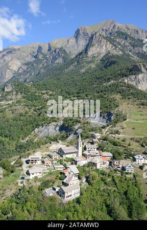 AERIAL VIEW. Small village at the foot of a majestic mountain. Saint-Marcelin, Hautes-Alpes, France. Stock Photo