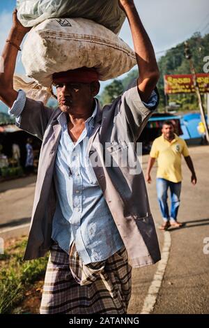 A man carrying two big bags on his head in Sri Lanka Stock Photo