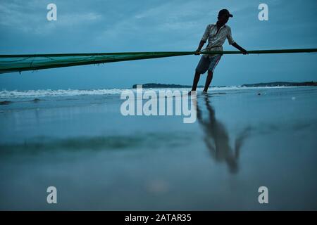 A fisherman gathering a fishing net on Arugam Bay beach in the early  morning. Arugam Bay is a small fishing town on the east coast of Sri Lanka  Stock Photo - Alamy