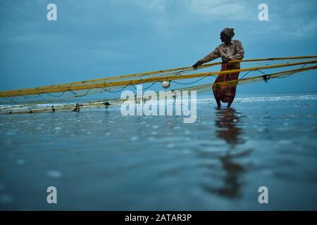 Fisherman pulling the nets out of the ocean on the beach in Sri Lanka. Town of Trincomalee has big and long beach where locals pull nets and fish. Stock Photo