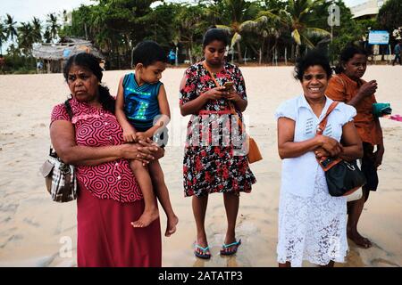 Sri Lankan families enjoying free time on a tropical beach in Trincomalee. Stock Photo