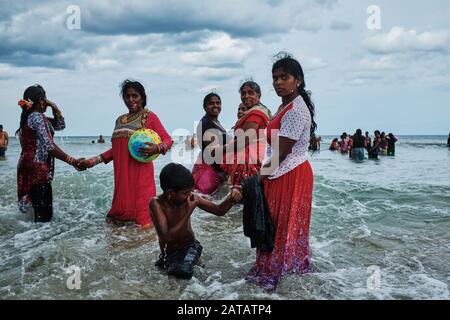 Sri Lankan families enjoying free time on a tropical beach in Trincomalee. Stock Photo