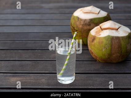 Tropical fresh coconut water in glass on wooden background Stock Photo