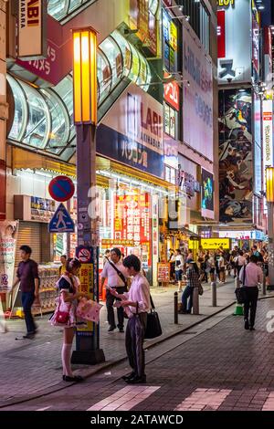 Tokyo, Japan, August 13, 2019 – A young man approaching a maid in Akihabara district at night Stock Photo