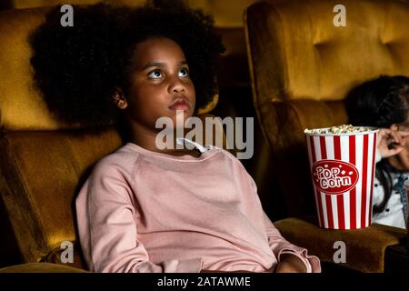 Two children african and asian having fun and enjoy watching movie in cinema Stock Photo