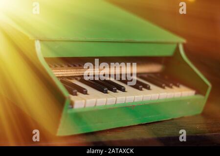 Morning sun rays illuminate the toy piano. Vintage wooden toy in the attic of an old house. Close-up. Selective focus. Blurred background. Stock Photo