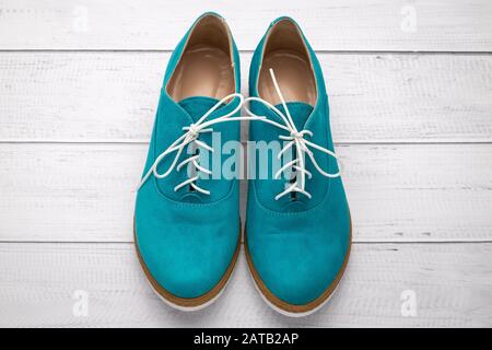Pair of suede shoes aqua color. Green boots with white laces on a light wooden background, top view Stock Photo