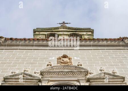 Bell tower of a church with a metal cross on top and details carved in stone on the facade, west of Spain, in Serradilla (Caceres) Stock Photo