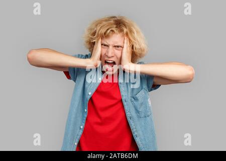 Young adult guy scream and holding hands on head Stock Photo