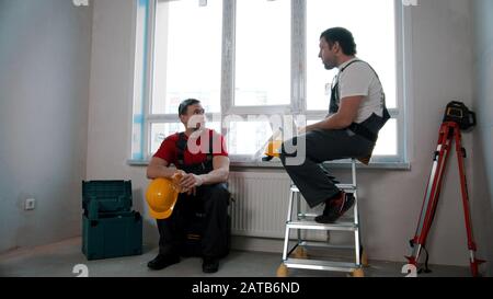 Men workers having a break and eating cheesy roll and apple Stock Photo