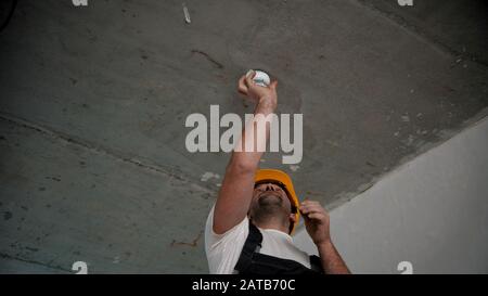 A man setting fire alarm on the top of the draft room Stock Photo