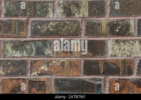 Horizontal close-up section of a weathered, multi-colored brick wall; background. Stock Photo