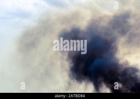 Exhaust pipe of ferry boat with black thick smoke coming out and sky with clouds on background. Air pollution. Stock Photo