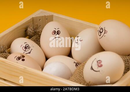 wooden basket filled with funny easter eggs on yellow background . Happy Easter Stock Photo