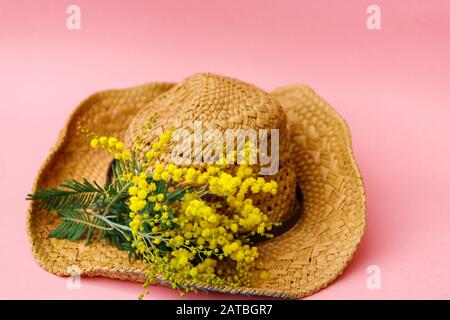 spring straw hat with mimosa on pink background Stock Photo