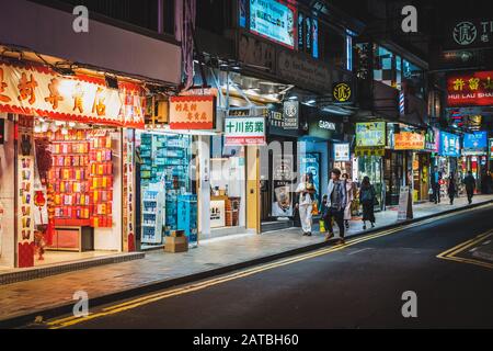 Hongkong, Hong Kong - November, 2019: Illuminated shops and people on shopping street at night in HongKong City, Tsim Sha Tsui Stock Photo