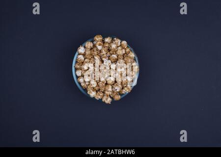 Caramel sweet popcorn bowl isolated on black background top view. Frame composition with copy space. Stock Photo