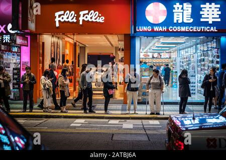 Hongkong, Hong Kong - November, 2019: People on street at night waiting for bus in HongKong City, Tsim Sha Tsui Stock Photo