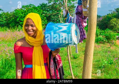 pretty young african woman hanging clothes on a line to dry outside after doing laundry Stock Photo