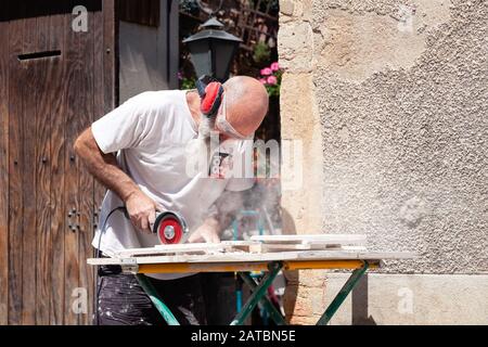 A man in safety glasses cuts metal with a special circular 