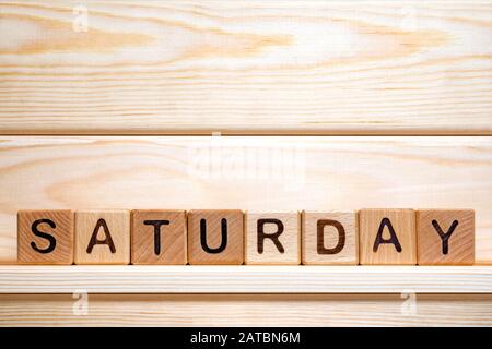 Saturday word written with vintage wooden cubes on wooden background. Day off background. Business concept. Small business. The word Saturday on wooden cubes. Weekday business concept. Stock Photo