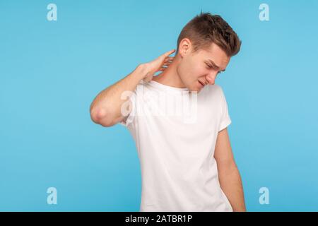 Portrait of unhealthy man in t-shirt massaging painful neck, hurting shoulders, suffering muscle tension from sedentary lifestyle, healthcare and medi Stock Photo