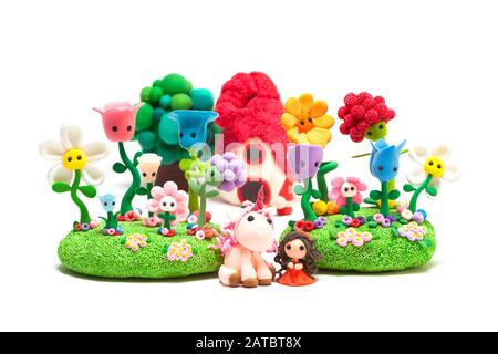 Modelling clay hand made red dressed little girl and unicorn in a fairy tale village Stock Photo