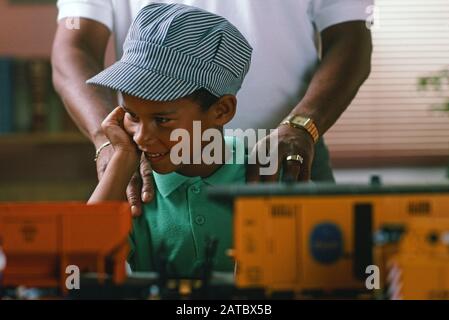 African-American Grandfather and grandson playing with a set of G gauge model electric trains Stock Photo