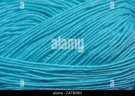 Beautiful closeup of a ball of natural organic turquoise wool forming a wavy pattern. Background with details of the soft and tender light blue fiber Stock Photo