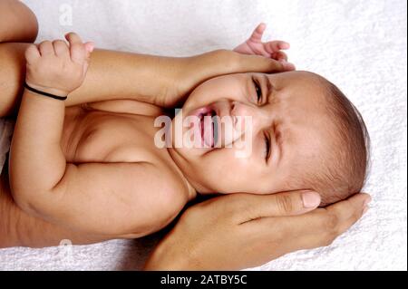 Mumbai; Maharashtra; India- Asia; Sep. 2011- Portrait of nine months indian cute little baby crying on white background Stock Photo