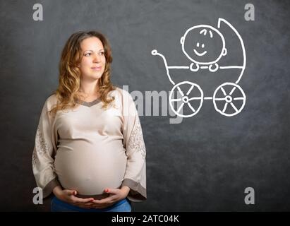 Pregnant woman imagines a future child in the stroller Stock Photo