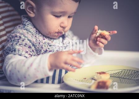 The nice baby with messy face eating cheese cakes Stock Photo