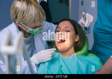 Professional male and female dentists examining woman's teeth in dental office Stock Photo