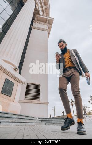 Modern hipster guy with long hair and beard at the city square